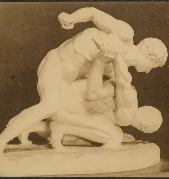 A sculpture of two nude male wrestlers locked in an athletic struggle, one pinning the other down.