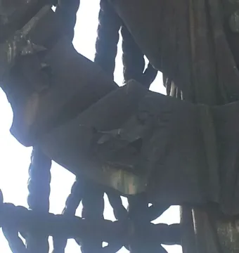Close-up of Birth of a New Man sculpture with a weathered metal surface, rope-like forms, and a large green-patinated limb against the sky.