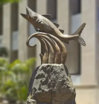 The Chicharro Sculpture showing a metallic fish leaping from a rugged rock pedestal.