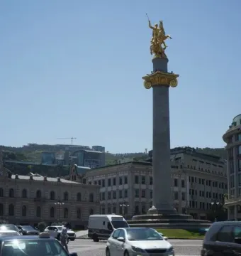 The Freedom Monument with a golden equestrian statue atop a tall column in a city square.
