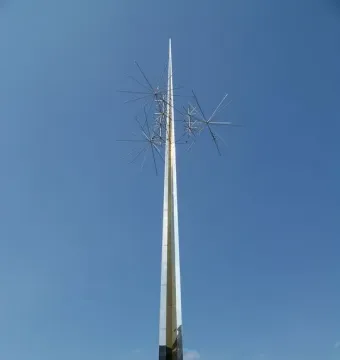 Ad Astra sculpture with a tall reflective spire and spiky star-like forms against a blue sky.