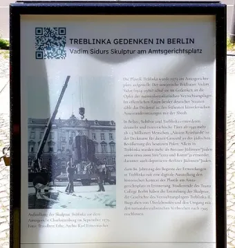 Outdoor information sign about Treblinka with German text, a QR code, and a historic black-and-white installation photo.