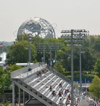 The Unisphere rises above trees and stadium stands under a hazy sky.