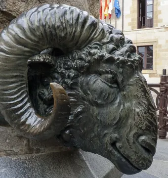 Close-up of the Monument to Viriato showing a dark metallic ram head with spiraled horns on a stone base.