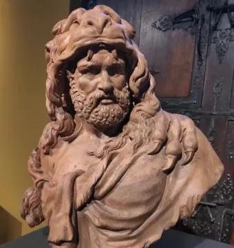 Bust of Hercules showing a bearded man wearing a heavy animal pelt over his head and shoulder.