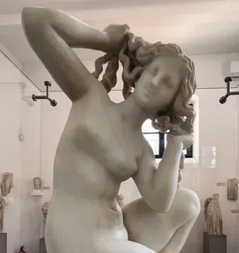 Crouching Venus, a white marble statue of a nude woman crouching with her hands raised to her hair.