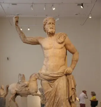 Poseidon of Melos marble statue of a bearded man with one arm raised, displayed in a museum gallery.