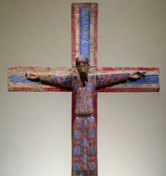 Batlló Majesty wooden crucifix showing Christ in a patterned red and blue tunic with outstretched arms.