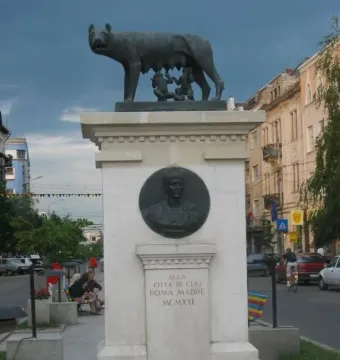 Capitoline Wolf sculpture of a she-wolf suckling two infants on a tall stone pedestal.