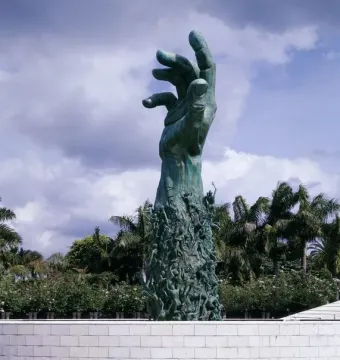 Holocaust Memorial sculpture in Miami Beach, a dark green raised arm and open hand rising above smaller figures and water.