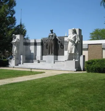 The Soldiers\' Monument, a stone and bronze memorial with two standing figures and a central bronze figure holding wreaths.