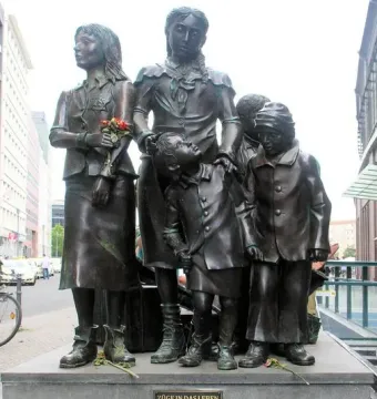 Trains to Life – Trains to Death monument showing several bronze children on a stone base with a plaque.