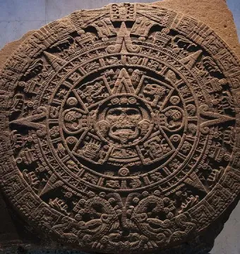 The Aztec Sun Stone carved as a large circular stone disc with a central face and concentric rings of symbols.