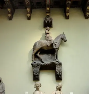 Stone equestrian statue of the Bamberg Horseman mounted on a wall, with a crowned figure on horseback and carved architectural details above.