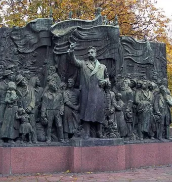 The Branting Monument in bronze, showing a central figure with a raised arm addressing a crowd of men, women, and children.