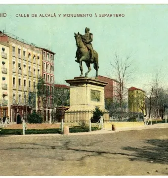 General Espartero Monument on a tall stone pedestal in a city square with surrounding buildings and bare trees.