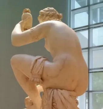 Giambologna\'s Venus seated on a column, wrapped in drapery and turned to the left.