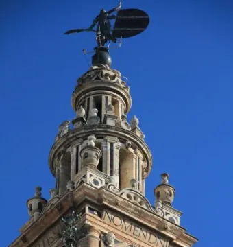 The Giraldillo weather vane atop the Giralda tower in Seville against a clear blue sky.