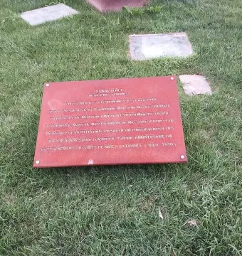 A reddish-brown information plaque for Neuf Lignes Obliques lies angled on green grass.