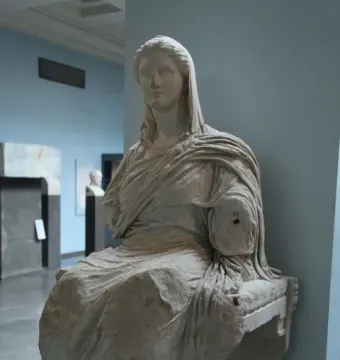 Demeter of Knidos seated marble statue with draped garments and missing forearms in a museum display