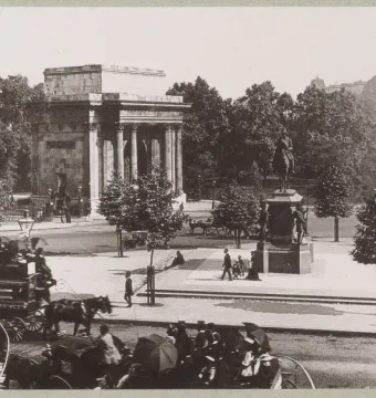The Duke of Wellington equestrian statue in front of Wellington Arch, with carriages and pedestrians on a London street.