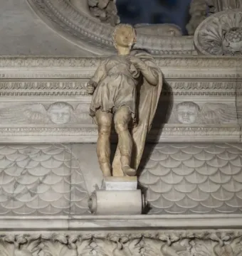 Marble statue of Saint Proculus standing before an ornate carved background with cherub heads and decorative friezes.