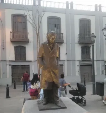 Bronze statue of César Vallejo on a stone pedestal in a paved square.