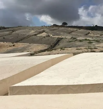 Il Grande Cretto stretching across a hillside in cracked concrete forms under a partly cloudy sky.