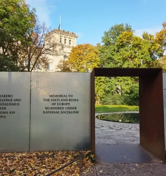 Entrance to the Memorial to the Murdered Sinti and Roma of Europe, with a dark archway and panels of text beside a circular water basin.