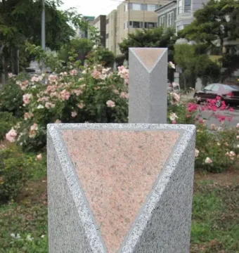 Pink Triangle Park memorial with two gray granite columns topped by pink triangles, set among grass and roses.