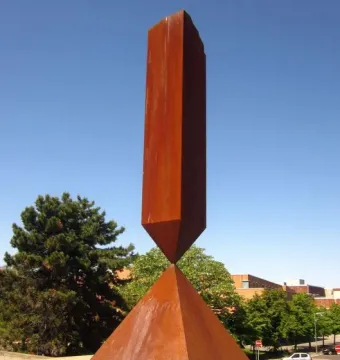 Broken Obelisk sculpture with a rust-colored metal base and tall rectangular column against a blue sky