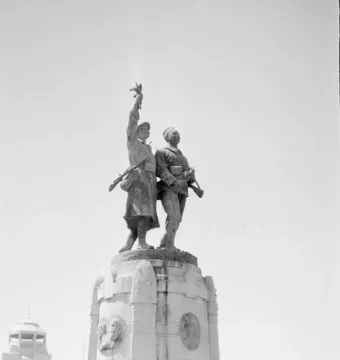 Demba et Dupont monument showing two military figures atop a tall stone pedestal with plaques and inscriptions.