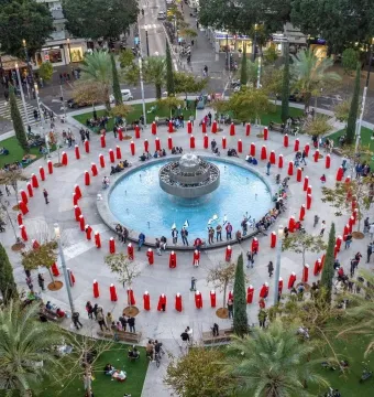 An aerial view of the Fire and Water Fountain at the center of Dizengoff Square, with people arranged in a spiral pattern around it.