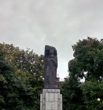 Karl Marx Monument on a tiered stone base in a paved plaza with trees behind it.
