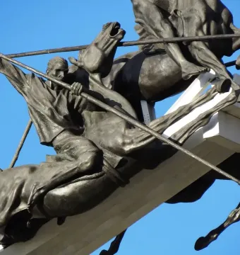Bronze horsemen statues from the Vargas Swamp Lancers monument against a blue sky.