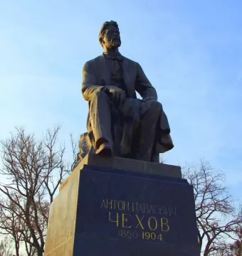 Chekhov Monument, a bronze seated statue of a bearded man on a pedestal against a blue sky