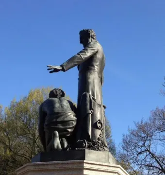 Emancipation Memorial bronze statue with Abraham Lincoln standing beside a kneeling figure on a stone pedestal.