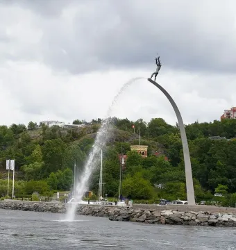 God our Father on the Rainbow sculpture with a water jet arcing from the raised figure into the bay.