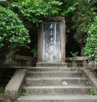 Weathered stone stele with Chinese inscriptions at the top of stone steps, surrounded by green foliage at Huangze Monastery.