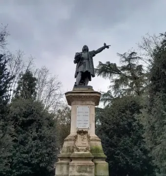 Monument to Columbus showing a bronze figure in period attire pointing outward on a tall stone pedestal.