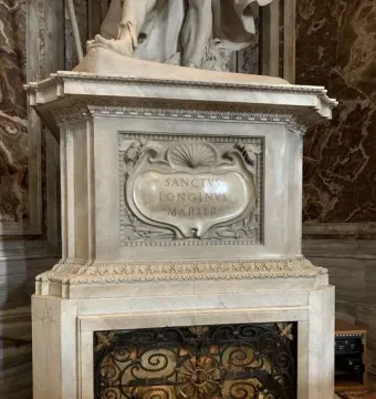 Marble pedestal with the inscription Sanctvs Longinvs Martyr, set above ornate black metal grates.