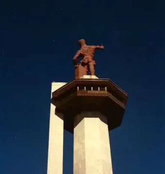 Vulcan statue atop a tall concrete pedestal against a dark blue sky.