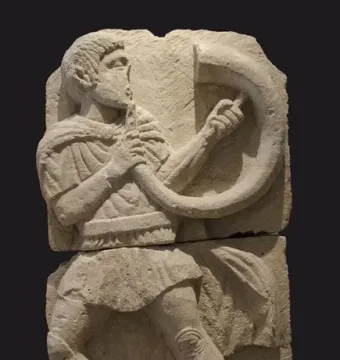 Acrobat from Osuna stone relief showing a male figure in a dramatic leaning pose holding a curved object.