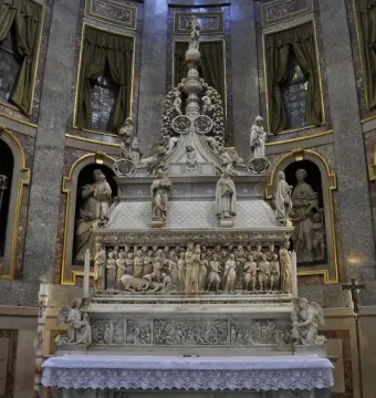 Arca di San Domenico, a white marble monument with sculpted figures and relief scenes inside a church interior.