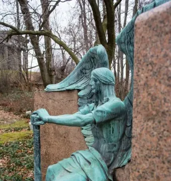 Haserot Angel, a weathered green-patinated winged figure beside a polished stone monument.