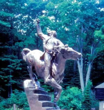 Israel Putnam equestrian statue of a man on horseback with one arm raised, set on a stone base amid trees and greenery.
