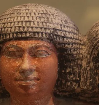 Close-up of the heads of the Raherka and Meresankh statues with textured headdresses and painted facial details.