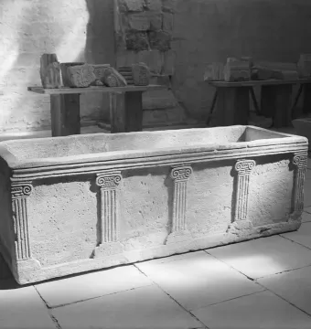 Sarcophagus of Louis the German, a rectangular stone chest with carved pilasters and Ionic-style capitals inside a museum space.