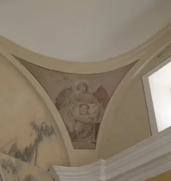 Faded fresco of an angel holding a cloth with a face, with the Latin inscription \