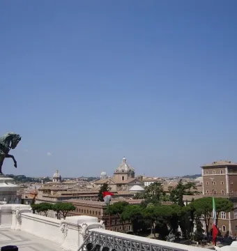 Victor Emmanuel II equestrian statue on a white marble pedestal overlooking Rome under a clear blue sky.